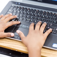 Two hands typing on a laptop keyboard