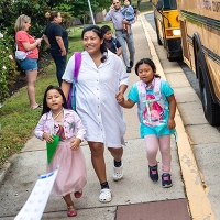 students entering the school building for the first day, guided by their parent. 