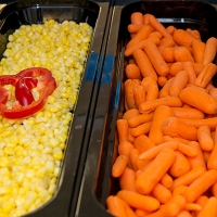 a bin of corn and a bin of carrots for a lunch line.