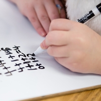 student writing addition problems on whiteboard